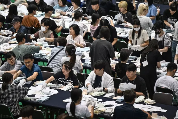 Des agents électoraux procédant au dépouillement de bulletins de vote lors d'une élection en Corée du Sud.