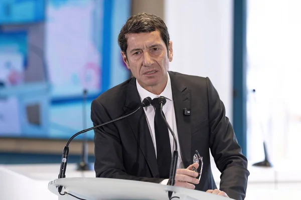 David Lisnard s'exprimant lors d'une conférence de presse, micros et pupitre blanc au premier plan.