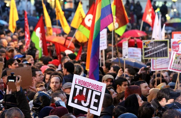 Manifestation contre l'homophobie à Paris, avec des pancartes et drapeaux LGBT.
