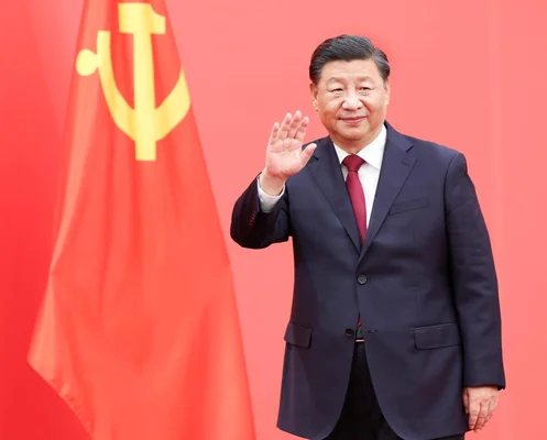 Xi Jinping, secrétaire général du Parti communiste chinois, agitant la main devant le drapeau du PCC