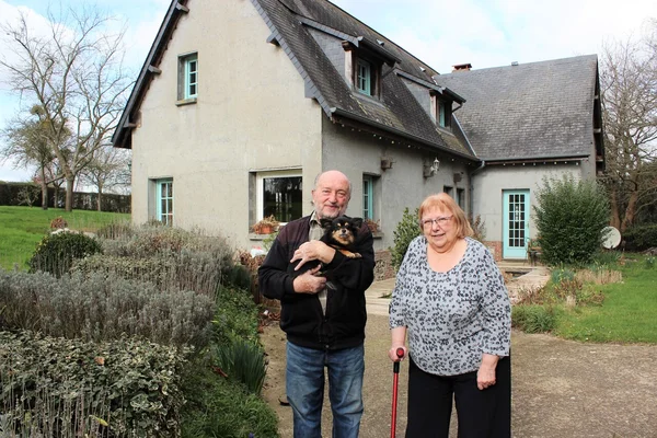 Un couple âgé devant leur maison, illustrant les difficultés liées aux saisies immobilières.