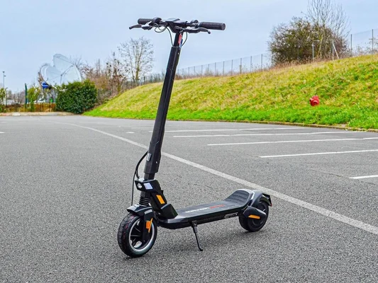 Trottinette électrique Dualtron Dolphin avec accents orange, garée dans un parking.