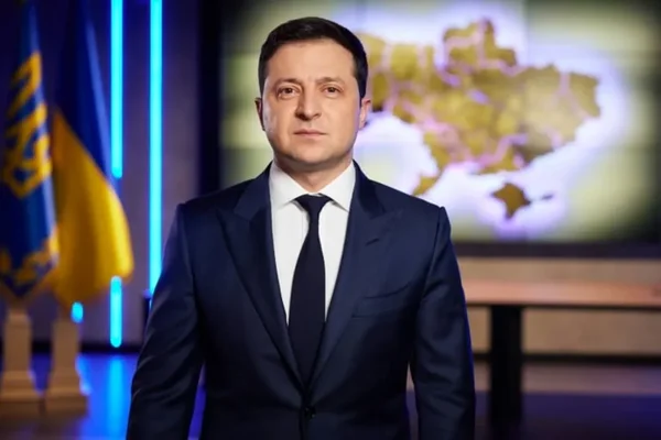 Volodymyr Zelenskyy devant un écran avec une carte et des drapeaux.