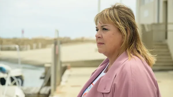 Michèle Bernier en veste rose près d'une marina.