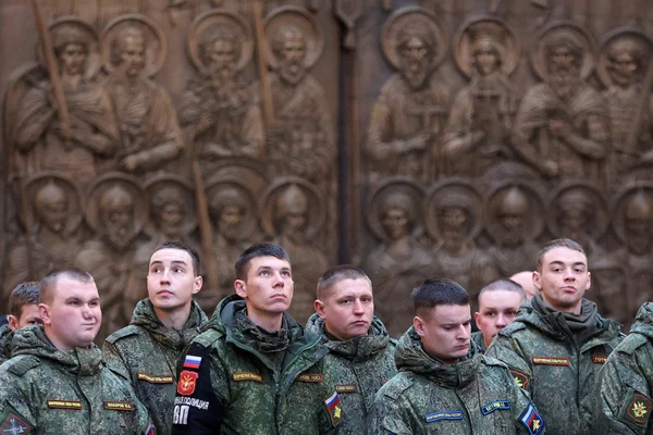 Membres de la Garde nationale russe (Rosgvardiya) en formation devant un bas-relief religieux.