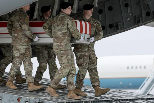 Des soldats américains transportant un cercueil drapé du drapeau des États-Unis lors d'une cérémonie de transfert digne.