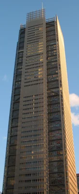 Le New York Times Building, gratte-ciel à l'exosquelette d'acier et à la façade vitrée, baigné de lumière dorée.