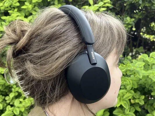 Une personne portant le casque Sony WH-1000XM6 noir, photographiée de profil devant un fond de verdure