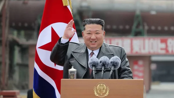 Kim Jong-un saluant lors d'un discours public avec le drapeau nord-coréen.