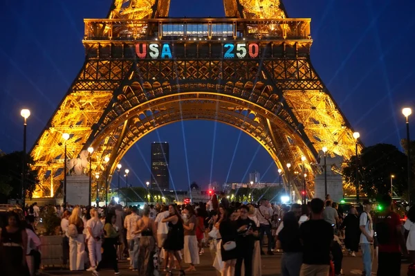 La tour Eiffel illuminée avec la projection 'USA 250' et des foules rassemblées, après l'escalade du drapeau américain