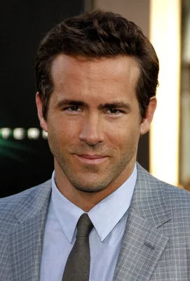 Ryan Reynolds en veste grise à carreaux et chemise bleue.
