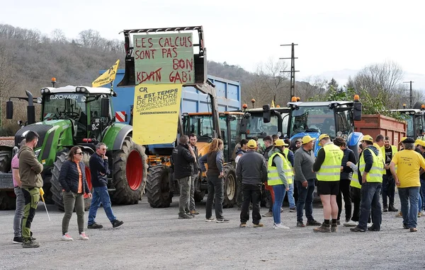 Agriculteurs en colère rassemblés avec des tracteurs et des banderoles lors d'une action de protestation.