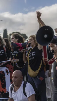 Manifestants avec des mégaphones et des t-shirts noirs lors d'une commémoration à Tel-Aviv.