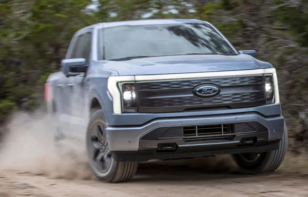 Ford F-150 Lightning bleu clair roulant sur un chemin de terre.