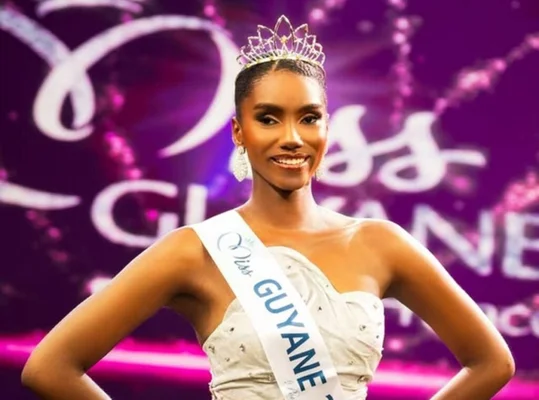 Sandra Justine, Miss Guyane 2026, posant en couronne et écharpe devant un fond violet.