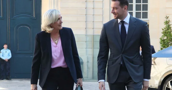 Marine Le Pen et Jordan Bardella quittant ensemble un bâtiment officiel.