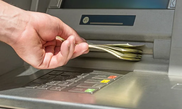 Retrait d'une liasse de billets à un distributeur automatique.