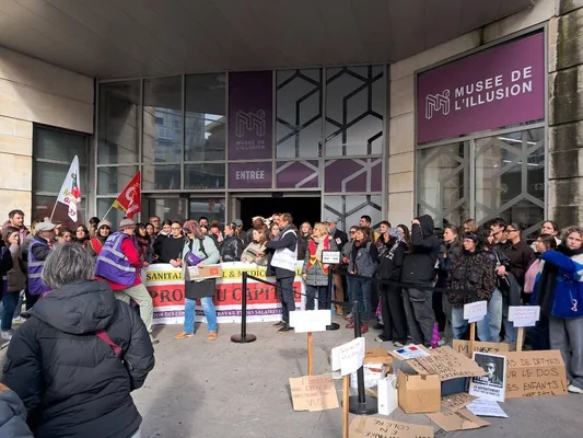 Rassemblement de manifestants devant le Musée de l'Illusion à Bordeaux, avec des pancartes pour la santé et les droits du travail.