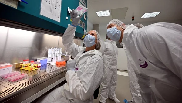 Des scientifiques en tenue de protection manipulent des échantillons dans un laboratoire de recherche sur le cancer.