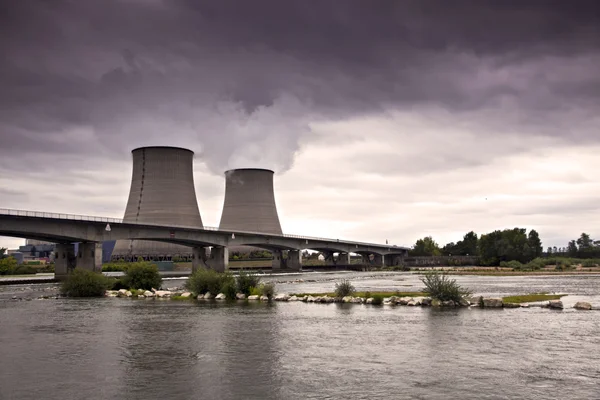 Tours de refroidissement d'une centrale nucléaire derrière un pont sur une rivière.
