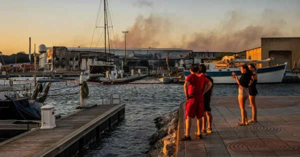 Des spectateurs observent un incendie dans une zone portuaire, illustrant la précocité des feux.