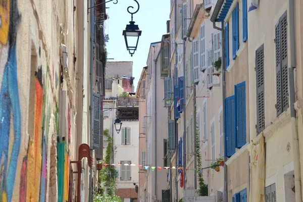 Une pittoresque ruelle du Panier, quartier emblématique de Marseille, avec ses volets bleus et ses plantes.