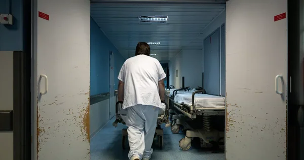 Couloir d'un hôpital avec des lits vides, illustrant les conditions dans les établissements de santé.