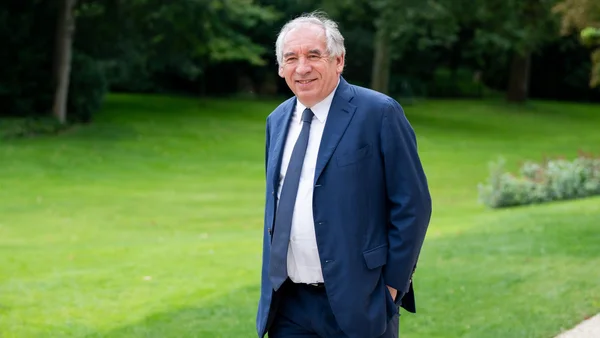 François Bayrou en extérieur, debout sur une pelouse.