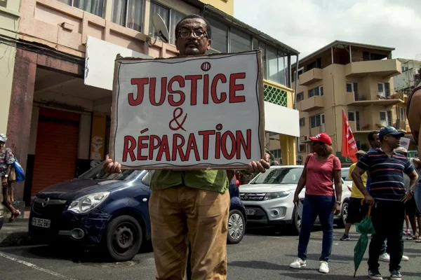Manifestant avec une pancarte 'Justice & Réparation' lors d'une protestation contre le chlordécone.