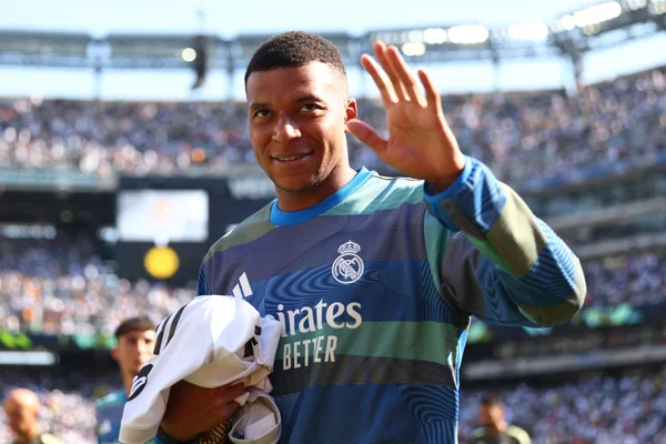 Kylian Mbappé saluant la foule lors d’un match du Real Madrid, vêtu de la tenue d’entraînement.