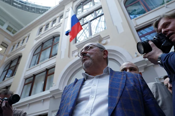 Boris Nadejdine entouré de photographes, drapeau russe en arrière-plan.