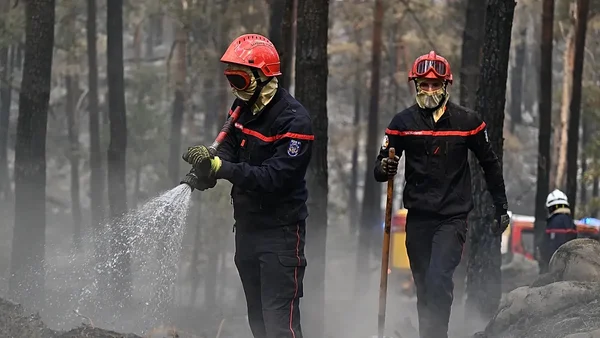 Pompiers luttant contre un incendie dans une zone boisée près de l'aéroport de Bordeaux.