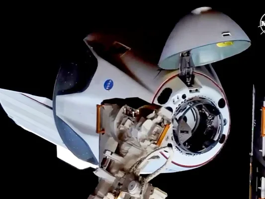 La capsule Crew Dragon de SpaceX amarrée à l'ISS, avec le logo de la NASA visible sur le côté.