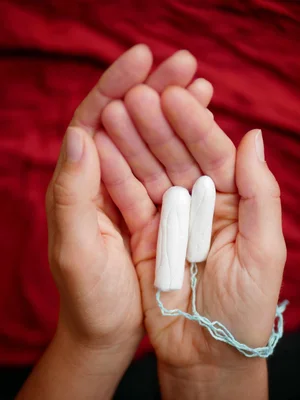 Deux tampons hygiéniques blancs tenus dans des mains, au cœur du rapport de la FDA.