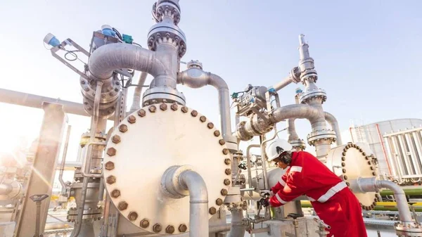 Ouvrier inspectant des vannes sur une installation pétrolière, illustrant la chasse aux fuites de méthane.