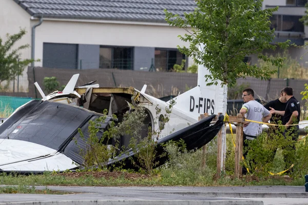 Vue de l'épave de l'avion D-FIPS à Tomblaine, avec des curieux derrière le ruban de sécurité.
