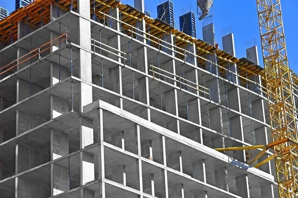 Immeuble en béton en construction, potentiellement une batterie gravitaire, avec grue et coffrage jaune.