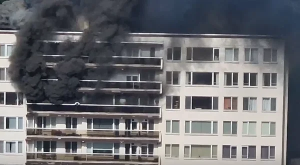 Incendie actif dans un immeuble à Anvers, avec une épaisse fumée noire s'échappant des étages supérieurs.