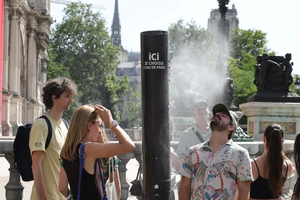 Des citadins se rafraîchissent près d'une fontaine à eau de Paris lors d'une journée de forte chaleur.