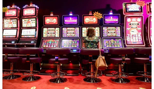 Joueuse dans un casino JOA, devant des machines à sous aux écrans lumineux.