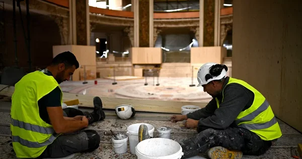 Travaux de rénovation au Palais de la découverte : des ouvriers dans le grand hall en chantier.