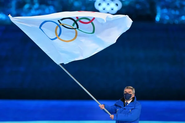 Un représentant du CIO tenant le drapeau olympique lors d'une cérémonie.