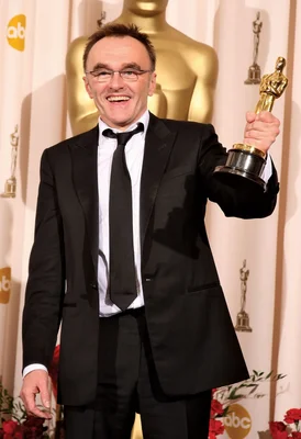 Danny Boyle célébrant sa victoire aux Oscars, statuette en main.