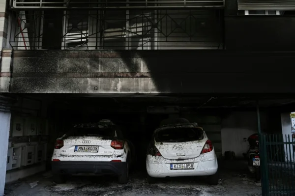 Deux voitures blanches recouvertes de cendres dans un garage après l'attentat à Athènes.