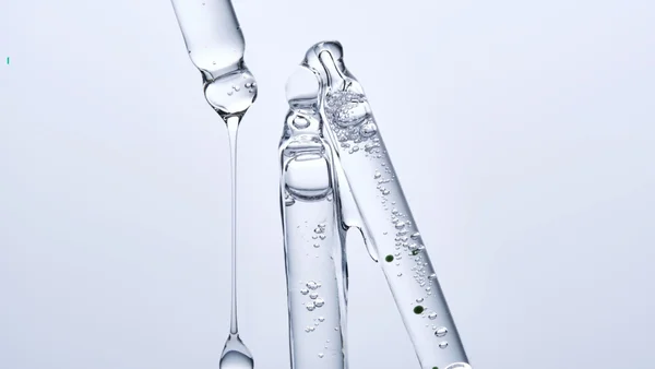 Liquide visqueux s'écoulant d'un compte-gouttes en verre, évoquant les préparations de peptides vendues en ligne.