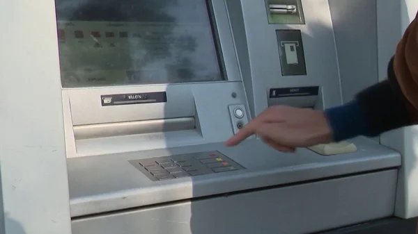 Utilisation du clavier d'un distributeur automatique de billets en extérieur.