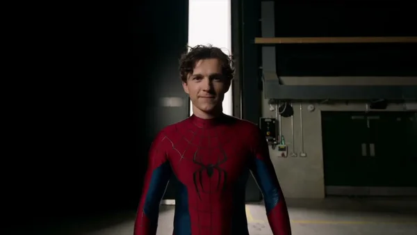 Tom Holland en Spider-Man sur le tournage, dans un décor industriel éclairé.