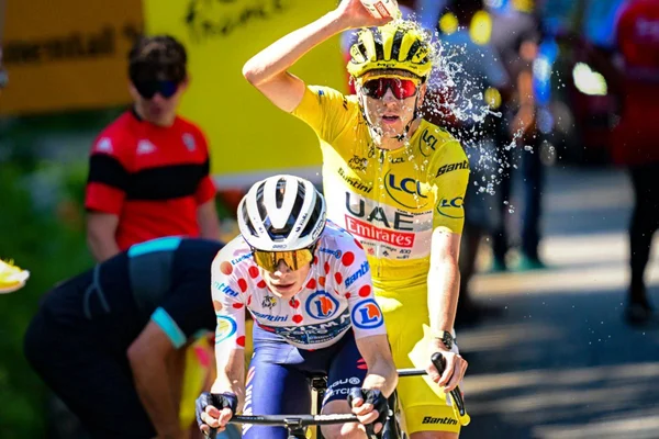 Le maillot jaune et le maillot à pois du Tour de France roulent côte à côte, rafraîchis par une aspersion d'eau.