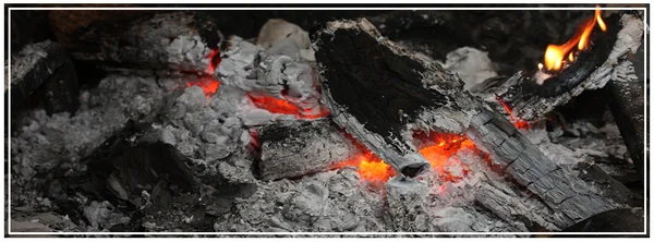 Bois brûlant et braises recouvertes de cendres.