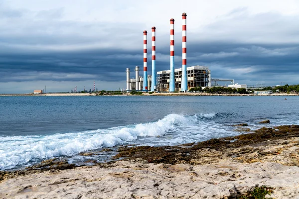 Centrale électrique côtière avec cheminées rayées rouges et blanches.